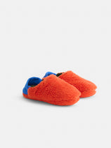 Sherpa House Shoes: fuzzy, orange, machine-washable slippers with blue heel accents, inspired by Japanese house shoes, shown on a white background.