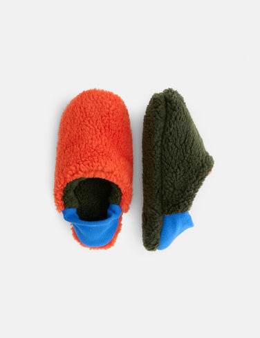 Two Sherpa House Shoes with a fuzzy texture inspired by Japanese house shoes: one orange with a green sole (top view) and one green with an orange sole (side view). Both feature blue elastic cuffs.