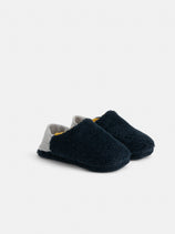 A pair of Sherpa House Shoes, cozy navy blue, with fuzzy texture, grey heels, and yellow inner lining, are machine washable and shown on a plain white background.