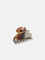The Large Round Claw is a brown and cream marbled hair clip with curved edges and interlocking teeth, handcrafted in France. It stands upright against a plain white background.