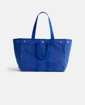 The Perfect Weekend Tote by Alex Mill is a roomy royal blue cotton canvas bag with two handles and snap button details, ideal for monogramming and shown against a plain white background.