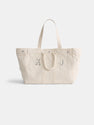 The Painted Perfect Weekend Tote is a spacious off-white canvas bag with two handles, silver rivets along the top edge, and light gray "K J" initials printed on the front.