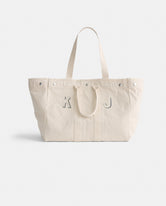 The Perfect Weekend Tote is a spacious off-white cotton bag with two handles and silver rivets. Featuring gray 