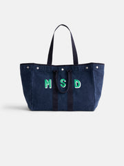 The Perfect Weekend Tote: a spacious navy blue cotton bag with two handles, decorative stitching, and green and white MSD monogram on the front—one of our stylish monogrammable bags, shown against a plain white background.