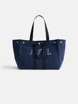 The Perfect Weekend Tote, a spacious navy blue cotton bag with two handles, silver button accents, and "JFL" embroidered on the front, is shown against a plain white background.