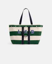 The Perfect Striped Weekend Tote features wide green and white canvas stripes, dark handles, and bold blue 