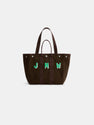 The Painted Perfect Weekday Tote is a brown cotton bag with dark handles and the green initials “JMW” embroidered on the front. This personalized tote features a structured silhouette and silver snap accents near the top edge.