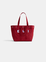 The Perfect Weekday Tote: a red cotton bag with two handles and white and blue "E L I" letters on the front, shown against a plain white background—a stylish monogrammable tote for everyday use.