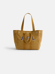 The Perfect Weekday Tote, a tan suede bag with two handles, features large blue and white "JFL" initials on the front and is shown against a plain white background.