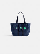 The Painted Perfect Weekday Tote is a spacious navy blue bag featuring two sets of handles and green-outlined "MSD" letters on the front, shown against a plain white background.