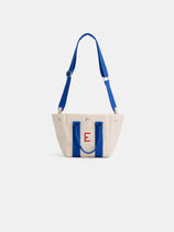 The Painted Mini is a small beige canvas tote bag with bright blue handles and strap, featuring an embroidered red letter E on the front. The bag is photographed against a plain white background.