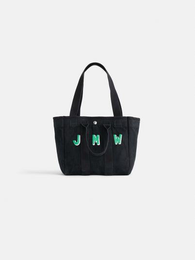 The Painted Perfect Daily Tote is a black bag with two handles, featuring the initials JMW in green and white on the front, shown against a plain white background.