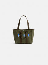 The Painted Perfect Daily Tote is an olive green canvas bag with two brown handles and blue embroidered "DMR" letters on the front, displayed against a plain white background.
