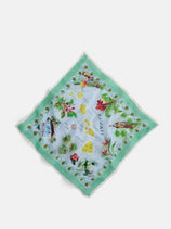 The State Bandana In Cotton Voile features illustrated maps, Hawaii landmarks, and tropical motifs—flowers, palms, hula dancers—on a pale blue background with a light green border, evoking vintage charm.