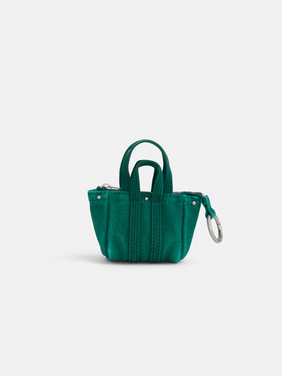 The Teeny Tiny Tote Keychain is a small green fabric tote with two handles, silver rivet details, visible stitching, and a metal keyring on one side, shown against a plain white background.