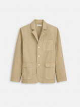 The Mill Blazer In Vintage Twill is a beige 100% cotton Alex Mill blazer with notched lapels, four buttons, and three front patch pockets, displayed on a white background.