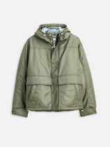 The Micah Parka In Nylon is an olive green hooded puffer with quilted insulation, military-inspired details, front zipper and snap buttons, large pockets, and a subtle shine, shown on a plain white background.
