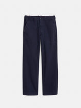 The Field Pant In Herringbone is a straight-leg vintage military style in dark navy blue, made from herringbone fabric with front patch pockets, belt loops, and a button-zip closure, shown flat on a white background.