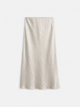 The Claire Skirt is a long, off-white women’s skirt with a simple straight silhouette and slightly crinkled texture, perfect for day-to-night wear, shown flat on a white background.