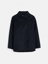 The Sophia Coat In Wool is a dark navy blue, double-breasted peacoat featuring black buttons, long sleeves, a high collar, and hand-finished wool. Shown against a plain white background.