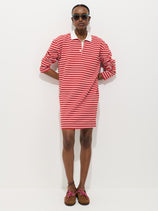 A person wears the Lizzy Rugby Stripe Dress in cotton jersey with red and white stripes, brown shoes with pink laces, and sunglasses, standing against a plain white background.