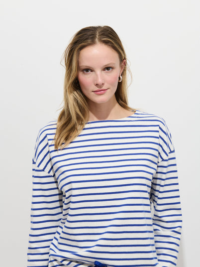 A young woman with long blonde hair, wearing the Avignon Striped Tee In Cotton, stands against a plain white background and looks at the camera with a neutral expression.